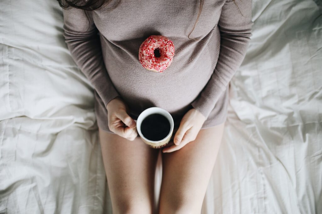 Pregnant belly with donut and coffee